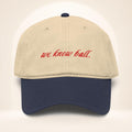 Front view of the We Know Ball Heritage two-tone Navy and Khaki garment-washed baseball cap with red script embroidery