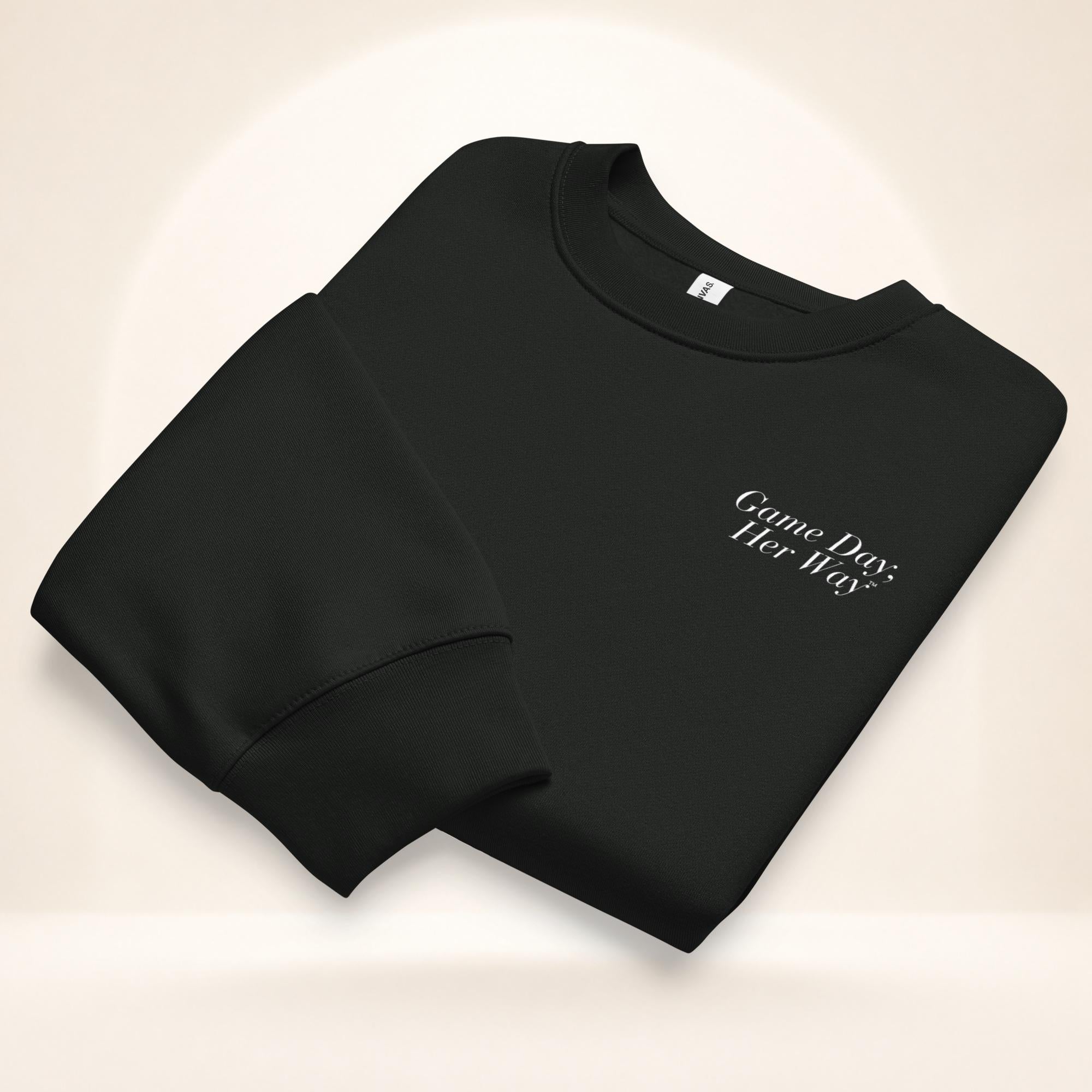 Folded black “We’re Friends… Unless It’s Game Day.” oversized unisex crewneck sweatshirt with a small embroidered “Game Day, Her Way.™” logo on the front left chest.